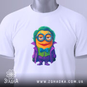 Футболка міньйон злодій джокер, біла, складена на столі, фон світлий, принт з міньйоном у фіолетовому пальто, з зеленим волоссям та окулярами, з етикеткою з зеленим шнурком.