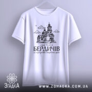 Футболка місто Бердичів подарунок, біла, підвішена на вішалці, фон світло-сірий, принт з архітектурним зображенням церкви та текстом на українській мові.
