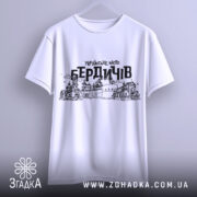 Футболка місто Бердичів, біла, зображена з фронтального ракурсу на манекені, фон світлий, принт містить чорний контурний малюнок архітектурних пам'яток Бердичева з написом 'УКРАЇНСЬКЕ МІСТО БЕРДИЧІВ'.