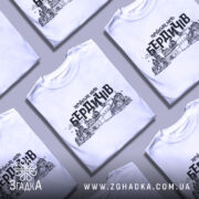 Футболка місто Бердичів, біла, зображена з фронтального ракурсу на манекені, фон нейтральний, принт містить чорний контурний малюнок архітектурних пам'яток Бердичева з написом 'УКРАЇНСЬКЕ МІСТО БЕРДИЧІВ'.