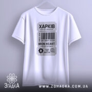 Футболка місто Харків, біла, підвішена на вішалці, фон світло-сірий, принт у вигляді етикетки з написом 'ХАРКІВ', деталі принта чітко видимі, акцент на наукову тематику.