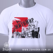 Футболка місто Житомир, біла, складена на поверхні, фон світло-сірий, принт червоного кольору з написом 'Житомир' та малюнком будівель.