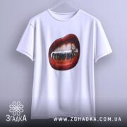 Футболка модна провокація, біла, підвішена на вішалці, фон світло-сірий, принт з червоними губами та золотими зубами, деталі з діамантом на одному з зубів.