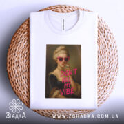 Футболка модний арт, біла, зображена на кошику з плетеного матеріалу, фон світло-сірий, принт з портретом жінки в рожевих окулярах, напис 'DON'T KILL MY VIBE' яскраво-рожевого кольору.