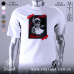 Футболка мої думки зайоби. Біла футболка на манекені, з принтом на чорному фоні, де зображена жінка в чорному вбранні з пістолетом. На принті червоні написи 'Мої думки' та 'Мої зайоби'. Фон світло-сірий, футболка має короткі рукави.