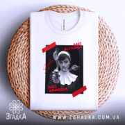 Футболка мої думки зайоби. Біла футболка, складена на плетеній основі, з принтом на чорному фоні, де зображена жінка з пістолетом. На принті червоні написи 'Мої думки' та 'Мої зайоби'. Фон світло-сірий.