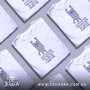 Футболка моя кукуха тримається на манекені, білого кольору, з принтом на грудях, зображаючим персонажа з піднятими руками, фон градієнтний сірий.