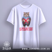 Футболка моє пузіко, біла, зображена з фронтального ракурсу, фон світло-сірий, принт з котом у синій футболці, текст червоного кольору, футболка висить на вішалці.