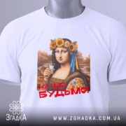 Футболка Мона Будьмо білого кольору, зображена зверху на плоскій поверхні, фон світло-сірий. Принт з жінкою у вінку з квітів, яка тримає стакан, з написом 'Ну що, Будьмо!' червоним кольором, на футболці також видно етикетку.