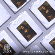 Футболка Мона Ліза білого кольору, зображена на манекені з правого боку, фон світло-сірий, принт з портретом Мона Лізи з написом 'Готична стабільність'.