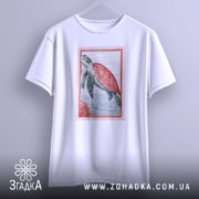 Футболка морська черепаха, біла, підвішена на вішалці, фон світло-сірий, принт з морською черепахою з червоною панцирем, оточена водою та коралами.