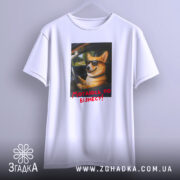 Футболка мотаюсь по бізнесу, білого кольору, підвішена на вішалці, фон світло-сірий, принт з коргі в окулярах, що сидить за кермом, з текстом "Мотаюсь по бізнесу!" червоного кольору.