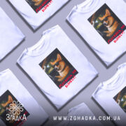 Футболка мотаюсь по бізнесу, білого кольору, зображена на манекені з правого боку, фон градієнтний сірий, принт з коргі в окулярах, що сидить за кермом, з текстом "Мотаюсь по бізнесу!" червоного кольору.