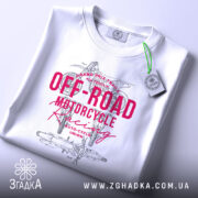 Футболка Мотокрос Гонки білого кольору, складена на поверхні, фон світлий, принт червоного кольору з текстом "OFF-ROAD MOTORCYCLE Racing" та ілюстрацією мотоцикла, на футболці є етикетка з зеленим шнурком.