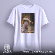 Футболка мотивуюча дівчина, біла, підвішена на вішалці, фон світлий, принт з дівчиною в традиційному вбранні, текст на українській мові: 'Чого тут думати? Треба робити!'.