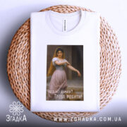 Футболка мотивуюча дівчина, біла, складена на плетеній основі, фон світлий, принт з дівчиною в традиційному вбранні, текст на українській мові: 'Чого тут думати? Треба робити!'.