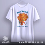 Футболка мовчання робить ягнят. Біла футболка з принтом, що зображає яскравого лева, підвішена на вішалці. Принт має насичені кольори: оранжевий, зелений та блакитний, текст на українській мові. Фон світло-сірий, ракурс фронтальний.