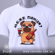 Футболка може винця білого кольору, складена на поверхні, фон світло-сірий, принт з мультяшним собакою, що тримає келих і пляшку, з етикеткою на комірці.