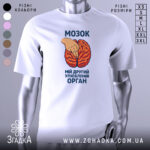 Футболка мозок другий орган. Біла футболка з принтом, на якому зображено червоний мозок та рука, що вказує на нього. Фон нейтральний, зображення з фронтального ракурсу. Текст на футболці чорного кольору.