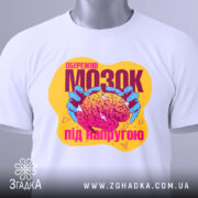 Футболка мозок під напругою, біла, знята з верхнього ракурсу, фон світло-сірий, принт яскравий з зображенням мозку в руках, з елементами графіки.
