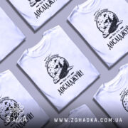 Футболка мрій і досліджуй, біла, зображена на манекені, фон світлий, принт з космічним кораблем та місяцем, текст 'Досліджуй!' внизу.