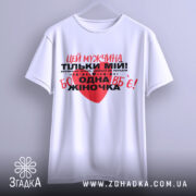 Футболка мужчина мій, біла, підвішена на вішалці, фон світло-сірий, принт червоний та чорний з текстом, що містить серце.