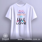 Футболка музика серця. Біла футболка з коротким рукавом, підвішена на вішалці, фон світло-сірий. Принт з текстом 'ALL YOU NEED IS LOVE' та силуетами людей, що йдуть, на кольорових трикутниках.