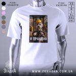 Футболка мила робота, білого кольору, зображена з фронтального ракурсу на манекені, фон нейтральний, принт з зображенням собаки в жовтій касці, текст "Я ПРАЦЮЮ" під ним.