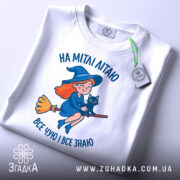 Футболка на мітлі літаю — чорна футболка, крупний план принта, студійне освітлення.