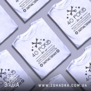 Футболка на оригінальних запчастинах, білого кольору, зображена з правого ракурсу на манекені, фон світло-сірий, принт чорного кольору з текстом "40 РОКІВ і все це на ОРИГІНАЛЬНИХ ЗАПЧАСТИНАХ" та зображенням ключів і зірочок.