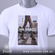 Футболка на завод, біла, зображена з верхнього ракурсу, фон світлий, принт з зображенням жіночих ніг у чорних колготках та туфлях на високих підборах, текст "НА ЗАВОД" великими літерами, на комірці видна етикетка.