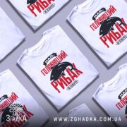 Футболка найголовніший рибак, біла, зображена з фронтального ракурсу на манекені, фон нейтральний, принт червоного кольору з чорним силуетом риби та текстом.