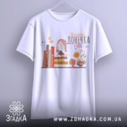 Футболка найкраща донечка, білого кольору, зображена з фронтального ракурсу на вішалці, фон світло-сірий, принт містить малюнок дівчинки в окулярах, що сидить на книжках, поряд з котом і квітами.