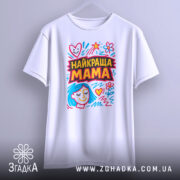 Футболка найкраща мама, біла, підвішена на вішалці, фон світло-сірий, принт з яскравими кольорами, з малюнком обличчя жінки з блакитним волоссям та сердечками.