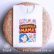 Футболка найкраща мама, біла, складена на плетеній основі, фон білий, принт з яскравими кольорами, з малюнком обличчя жінки з блакитним волоссям та сердечками.