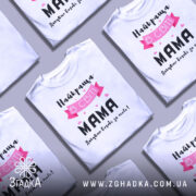 Футболка найкраща мама, білого кольору, зображена на манекені, фон світло-сірий, принт містить текст "Найкраща в світі МАМА" з рожевими елементами та сердечками.