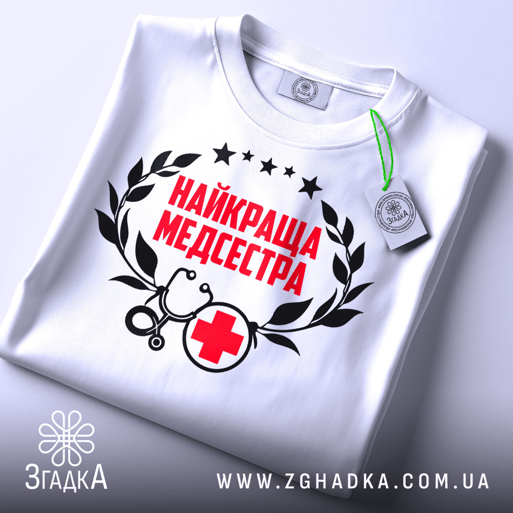Футболка найкраща медсестра, білого кольору, зображена зверху на плоскій поверхні, фон світло-сірий, принт містить червоний текст "НАЙКРАЩА МЕДСЕСТРА" з чорними елементами, на футболці є етикетка з зеленим шнурком.