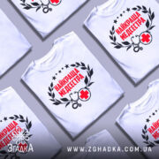 Футболка найкраща медсестра, білого кольору, зображена з фронтального ракурсу на манекені, фон світло-сірий, принт містить червоний текст "НАЙКРАЩА МЕДСЕСТРА" з чорними елементами у вигляді стетоскопа та червоного хрестика.