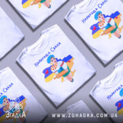 Футболка найкраща сваха, біла, зображена на манекені, фон нейтральний, принт з дівчиною в українському вбранні, яка тримає качалку і кошик з солодощами, на фоні контур України з жовто-синім кольорами.
