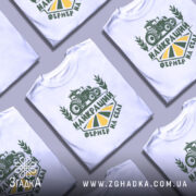 Футболка найкращий фермер, біла, зображена на манекені, фон нейтральний, принт зелений з трактором та написом 'НАЙКРАЩИЙ ФЕРМЕР НА СЕЛІ'.