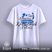 Футболка найкращий хрещений, біла, зображена на вішалці, фон світло-сірий, принт з текстом синього кольору та сердечками.