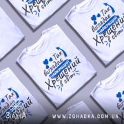 Футболка найкращий хрещений, біла, зображена на манекені, фон світло-сірий, принт з текстом синього кольору та сердечками.