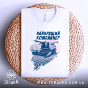 Футболка найкращий комбайнер, білого кольору, зображена в складеному вигляді на плетеній кошику, фон білий, принт з комбайном та написом виконаний у темно-синьому кольорі.