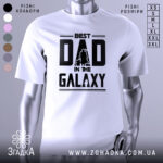 Футболка найкращий тато, біла, зображена на манекені, фон світло-сірий, принт чорний з написом 'BEST DAD IN THE GALAXY' та силуетами персонажів.