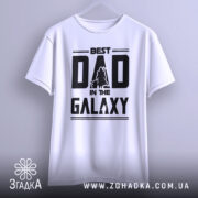 Футболка найкращий тато, біла, підвішена на вішалці, фон світло-сірий, принт чорний з написом 'BEST DAD IN THE GALAXY' та силуетами персонажів.