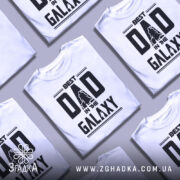 Футболка найкращий тато, біла, зображена на манекені, фон світло-сірий, принт чорний з написом 'BEST DAD IN THE GALAXY' та силуетами персонажів.