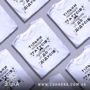 Футболка найкращий татусь, білого кольору, зображена на манекені, фон світло-сірий, принт чорного кольору з жовтими зірочками та малюнками окулярів і вусів.