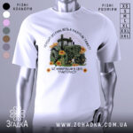 Футболка найкращий в світі тракторист. Біла футболка з принтом, на якому зображений зелений трактор серед соняшників. Фон світлий, футболка зображена в ракурсі спереду на манекені.