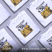 Футболка народжений в 90, біла, зображена на манекені, фон світлий, принт з жовтим магнітофоном і касетами, текст чорний, стильний і яскравий.