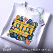 Футболка називайте мене дід. Біла футболка, складена на столі, з принтом, що містить жовтий напис 'ДІД' та ілюстрації грошових символів. На футболці є етикетка з зеленим шнурком. Фон світло-сірий, що надає акцент на деталі принта.